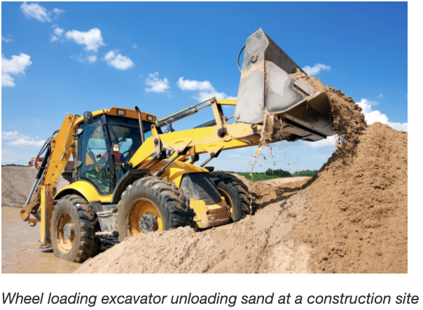 Wheel loading excavator unloading sand at a construction site.